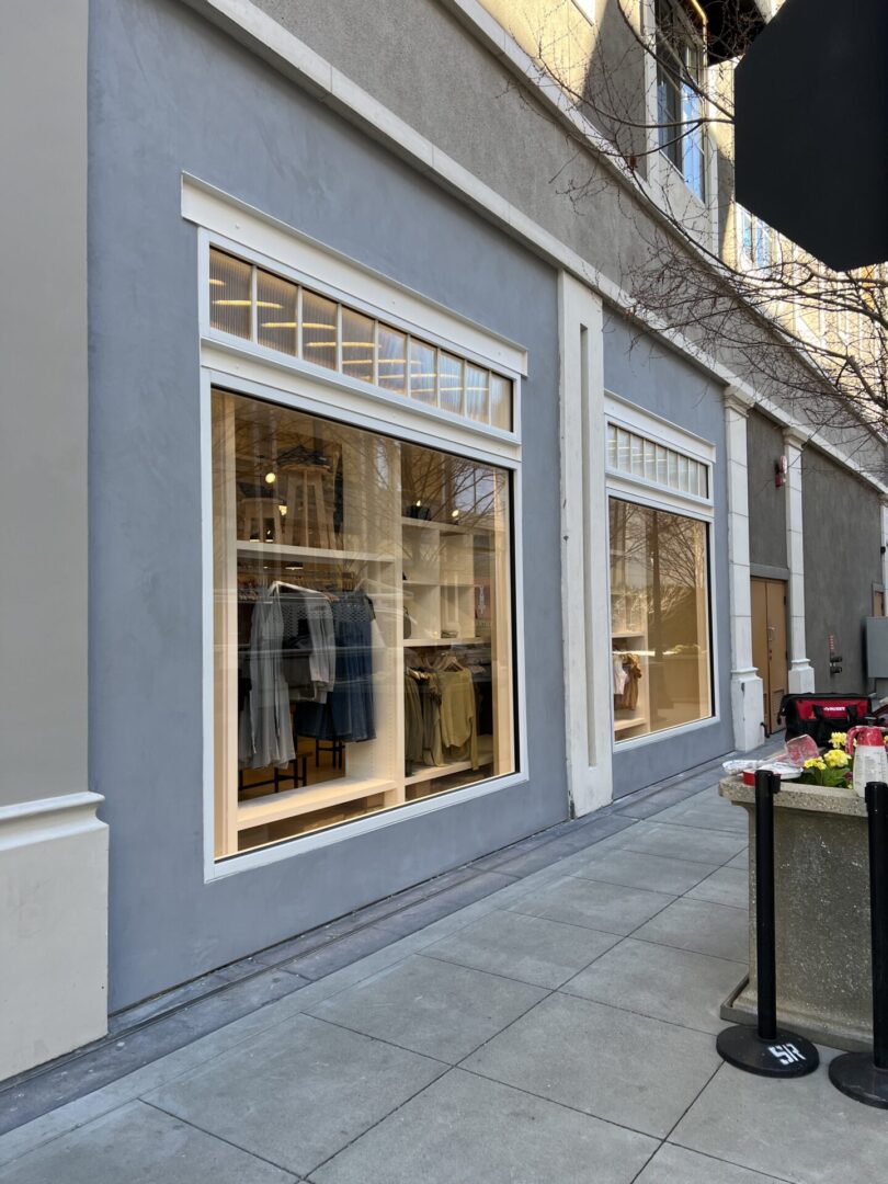 A store front with two windows and tables outside.