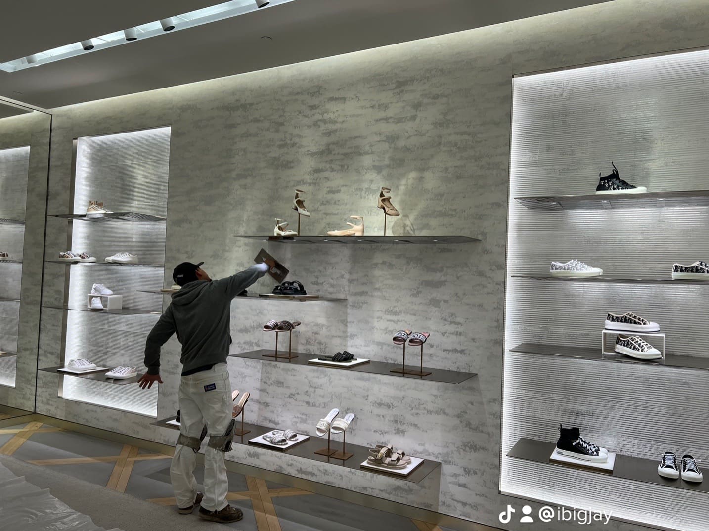 A man is standing in front of shelves with shoes on them.