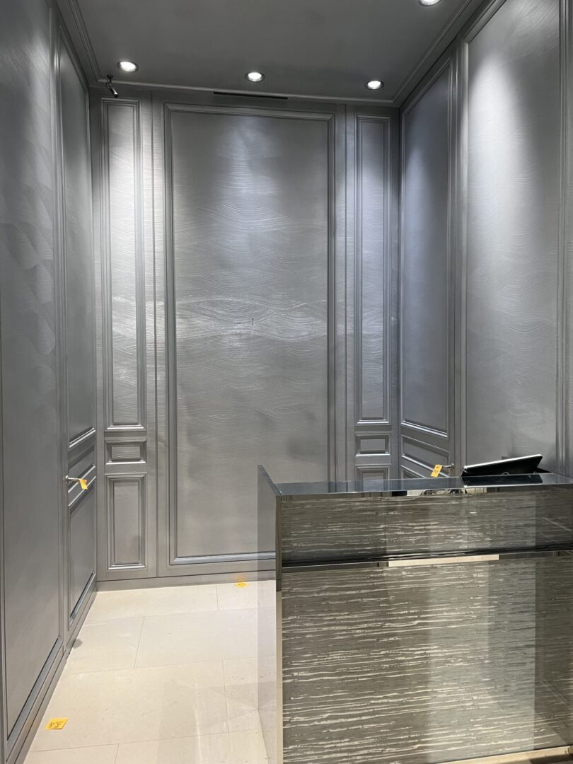 A silver elevator with two doors and a black counter.